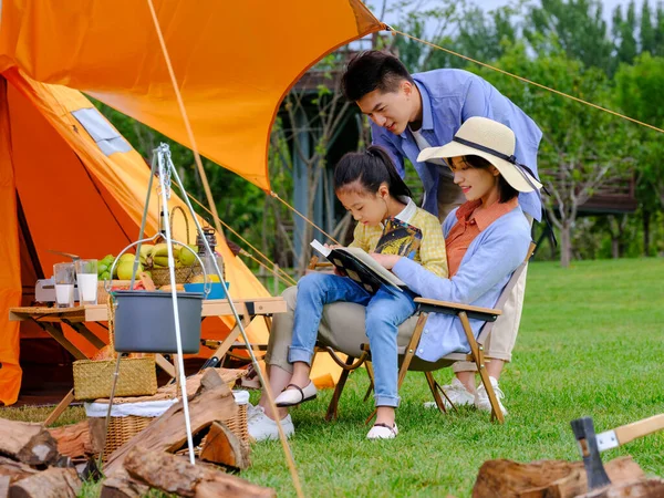 Szczęśliwa rodzina z trójką dzieci czytająca na zewnątrz — Zdjęcie stockowe