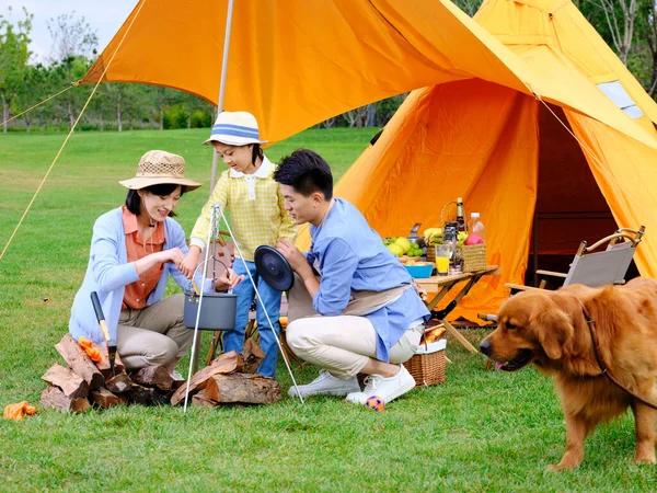 Boldog család három és kisállat kutya főzés szabadban — Stock Fotó