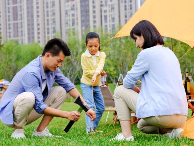 Üç kişilik mutlu bir aile dışarıda çadır kurmuş.