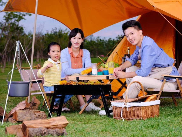 Una famiglia felice di tre persone che fanno barbecue nel parco — Foto Stock