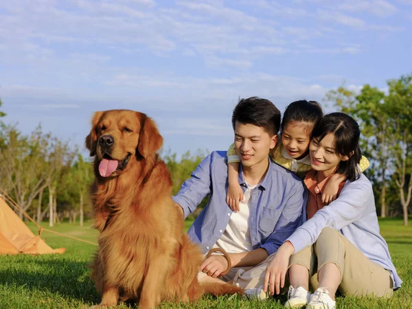 Família feliz de três e cão de estimação no parque — Fotografia de Stock