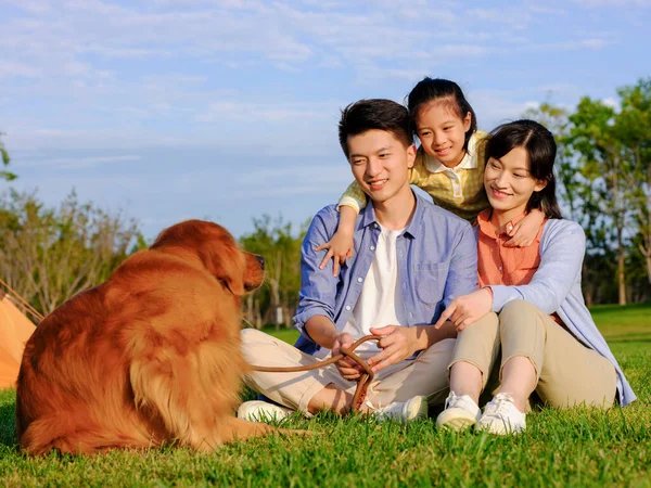 Família feliz de três e cão de estimação no parque — Fotografia de Stock