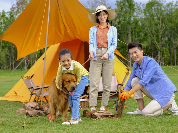 Šťastná trojčlenná rodina a pes táboří venku — Stock fotografie