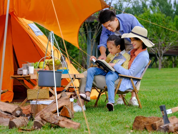 Una familia feliz de tres personas leyendo afuera —  Fotos de Stock