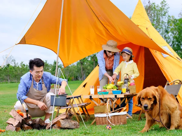 Familia feliz de tres y perro mascota cocina al aire libre Imágenes De Stock Sin Royalties Gratis