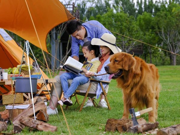 Famiglia felice di tre persone e cane da compagnia che legge fuori — Foto Stock