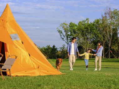 Parkta gezen üç köpekli mutlu bir aile.