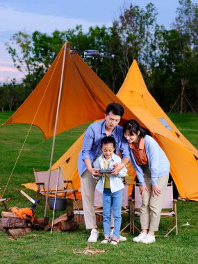Üç kişilik mutlu aile parkta İHA 'yı kontrol ediyor.