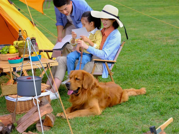 Üç kişilik mutlu bir aile ve dışarıda kitap okuyan bir köpek. — Stok fotoğraf