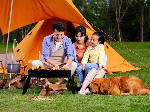 Boldog család három és kisállat kutya grill a parkban — Stock Fotó