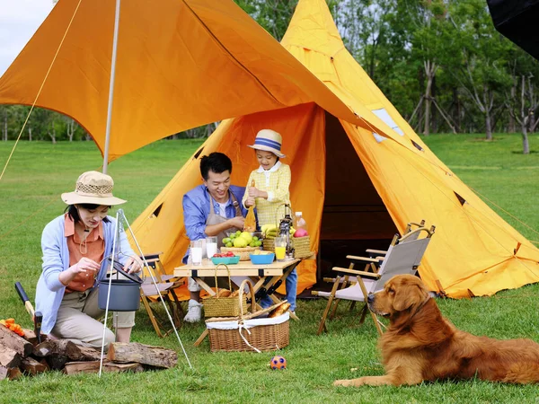 Familia feliz de tres y perro mascota cocina al aire libre — Foto de Stock