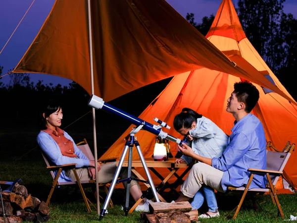 Une famille heureuse de trois personnes utilisant des télescopes à l'extérieur — Photo