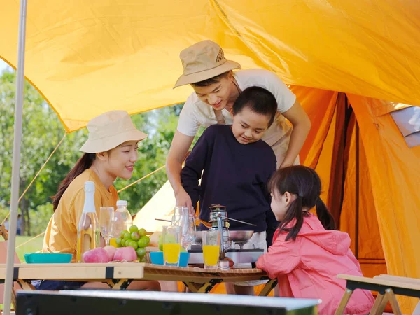 Счастливая семья из четырех человек устраивает пикник на открытом воздухе — стоковое фото