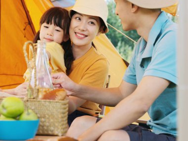 Üç kişilik mutlu bir aile dışarıda piknik yapıyor.