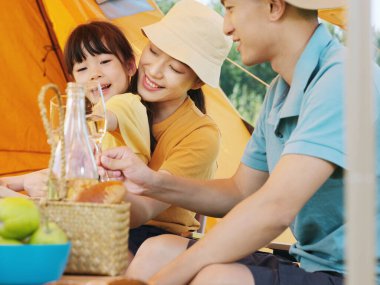 Üç kişilik mutlu bir aile dışarıda piknik yapıyor.