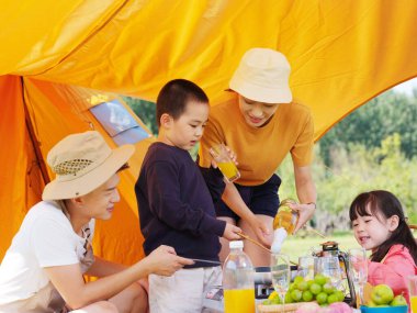 Dışarıda piknik yapan dört kişilik mutlu bir aile.