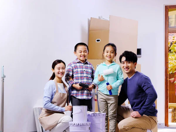 Uma família feliz de quatro decora sua casa — Fotografia de Stock