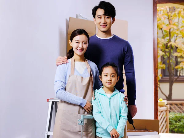 Uma família feliz de três decora sua casa — Fotografia de Stock