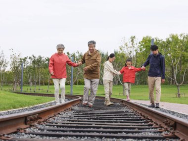 Dışarıda yürüyen beş kişilik mutlu bir aile.