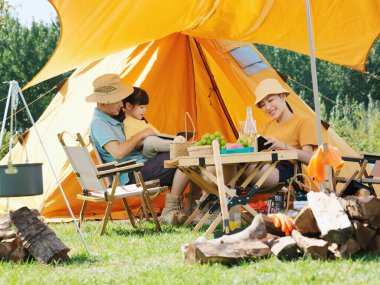 Dışarıda kitap okuyan mutlu bir aile.