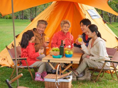Dışarıda piknik yapan beş kişilik mutlu bir aile.