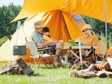 Dışarıda kitap okuyan mutlu bir aile.