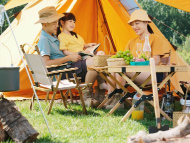 Dışarıda kitap okuyan mutlu bir aile.