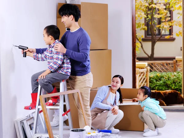 Uma família feliz de quatro decora sua casa — Fotografia de Stock