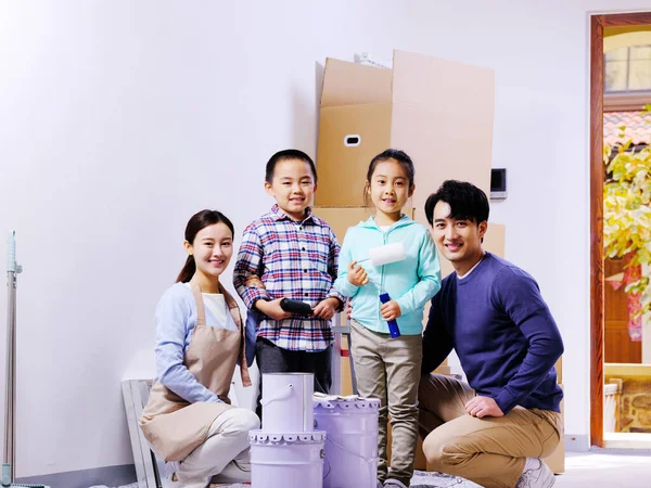 Uma família feliz de quatro decora sua casa — Fotografia de Stock