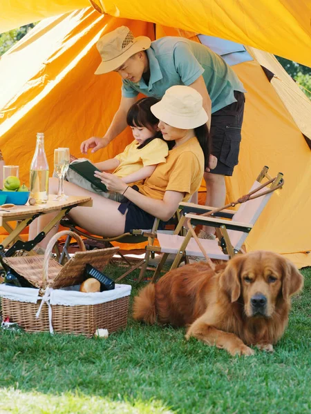 Heureuse famille de trois et chien de compagnie lisant à l'extérieur — Photo