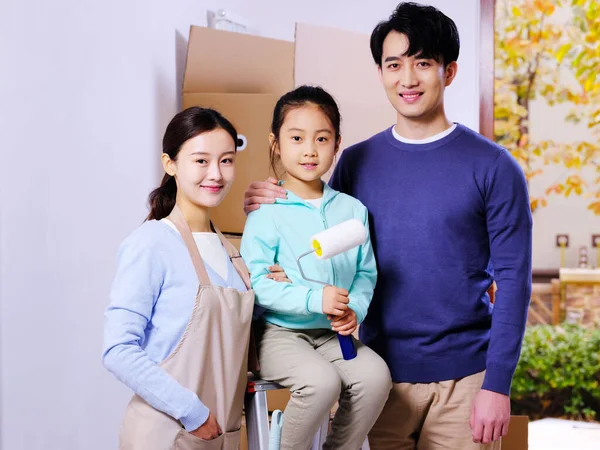 Una familia feliz de tres personas decora su casa — Foto de Stock