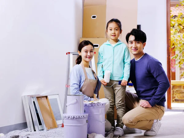 Uma família feliz de três decora sua casa — Fotografia de Stock