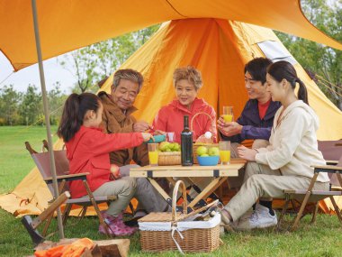 Dışarıda piknik yapan beş kişilik mutlu bir aile.