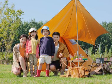 Dört kişilik mutlu bir aile ve parkta evcil bir köpek.