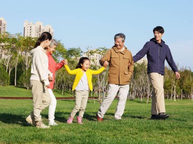 Beş kişilik mutlu bir aile parkta yürüyor.