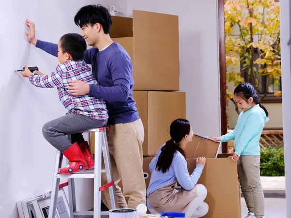 Uma família feliz de quatro decora sua casa — Fotografia de Stock