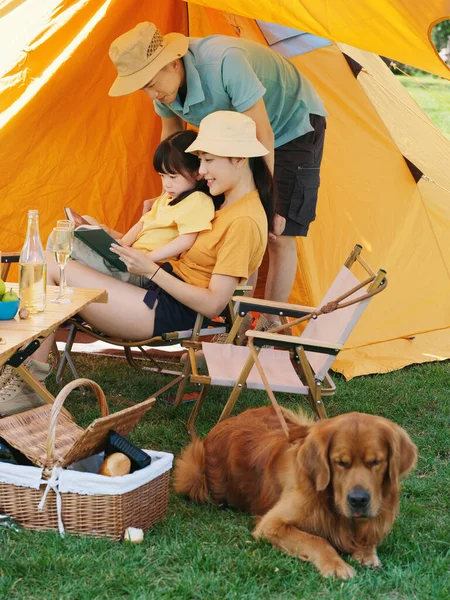 Glückliche dreiköpfige Familie und Hund lesen draußen — Stockfoto