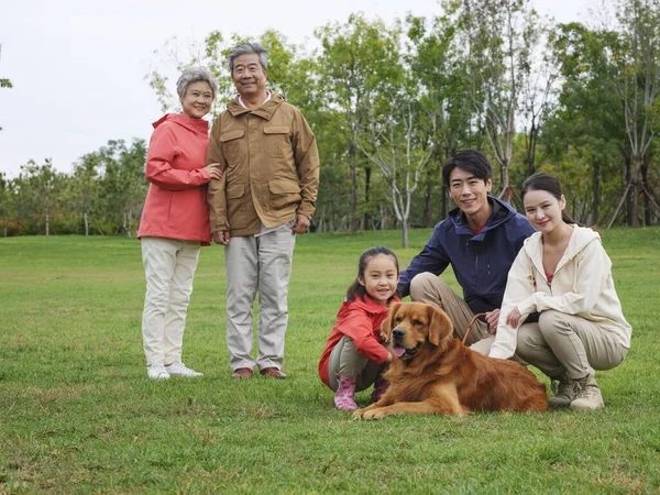 Mutlu beş kişilik bir aile ve parkta oynayan bir köpek. — Stok fotoğraf