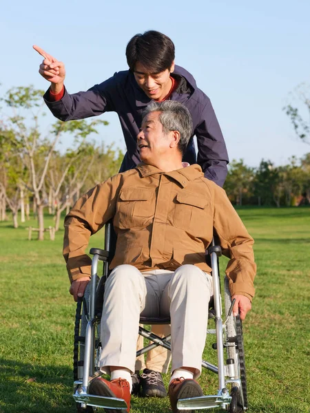 The young man pushed the old man in wheelchair for a walk