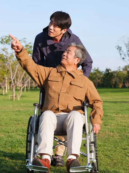 Den unge mannen knuffade gubben i rullstol för en promenad — Stockfoto