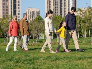 Beş kişilik mutlu bir aile parkta yürüyor.