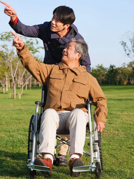 Den unge mannen knuffade gubben i rullstol för en promenad — Stockfoto