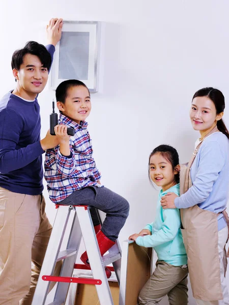 Uma família feliz de quatro decora sua casa — Fotografia de Stock