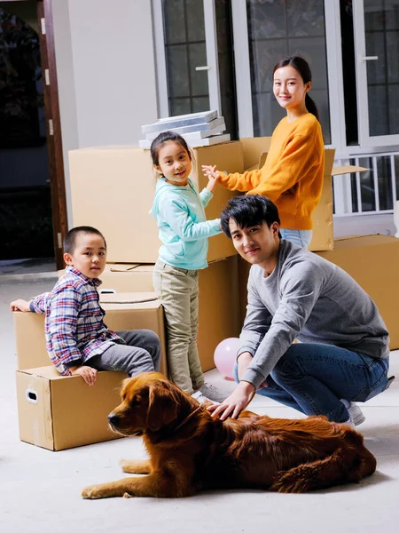 Una famiglia felice di quattro persone e il loro cane domestico stanno giocando nella stanza — Foto Stock