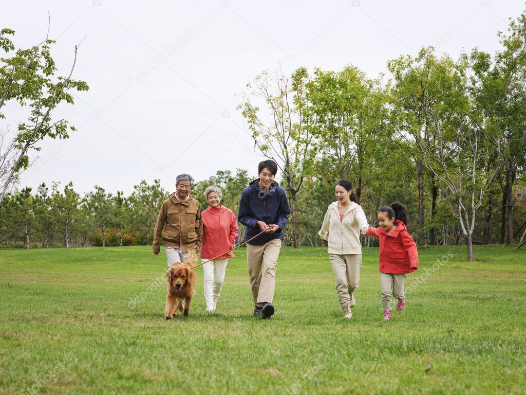 Happy family of five and pet dog walking in the park