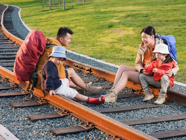 Família feliz de quatro pessoas sentadas na pista para descansar Fotografia De Stock