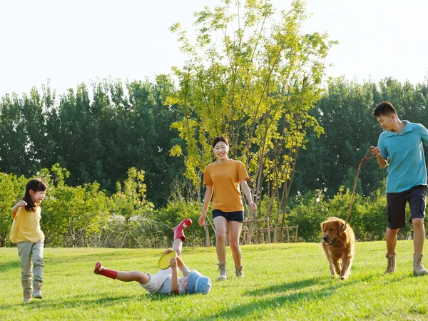 Happy family of four and pet dog playing in the park — Stock Photo, Image