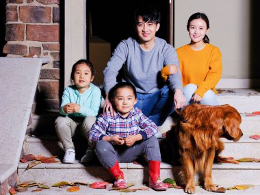 Dört kişilik mutlu bir aile evcil köpekleriyle merdivenlerde oturuyor.