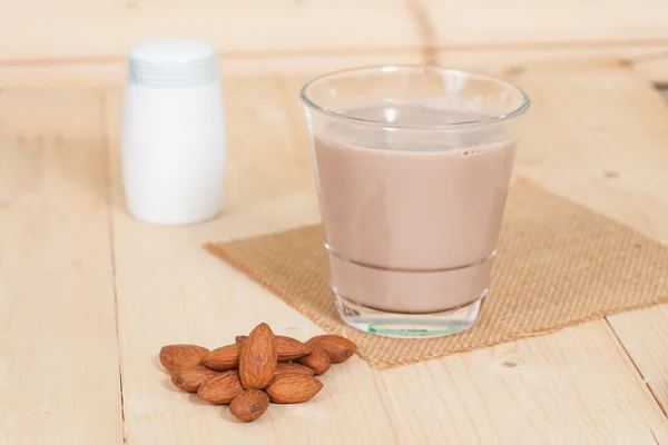 Mandorle in ciotola su fondo legno e latte al cioccolato — Foto Stock