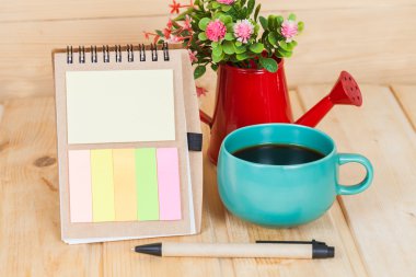 ahşap masa üzerinde Kupası ve vazo ile not defteri